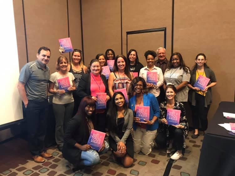 Workshop attendees holding The Self-Love Workbook